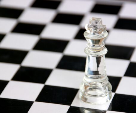 Clear king chess piece on black and white chess board