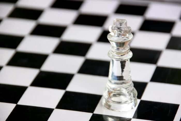 Clear king chess piece on black and white chess board