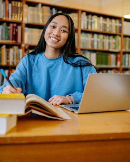 Woman in Blue Long Sleeve Shirt Sitting at the Table Smiling