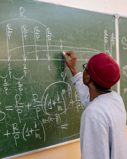 Back View of a Person Writing on a Blackboard