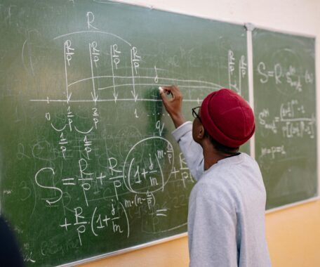 Back View of a Person Writing on a Blackboard