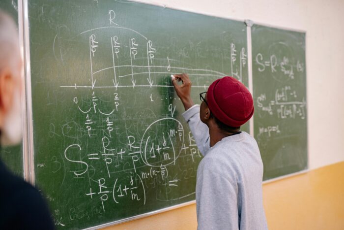 Back View of a Person Writing on a Blackboard