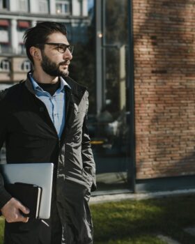 Man Wearing Black Jacket Holding Laptop Computer