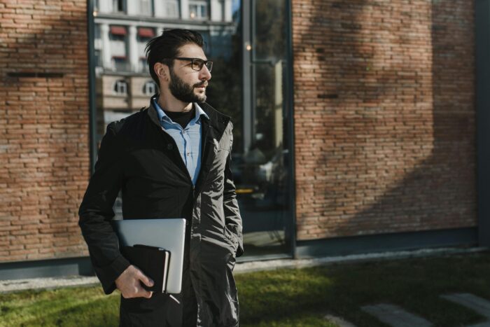 Man Wearing Black Jacket Holding Laptop Computer