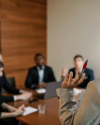 Woman in Gray Blazer Holding Pen Having Meeting with Her Colleagues