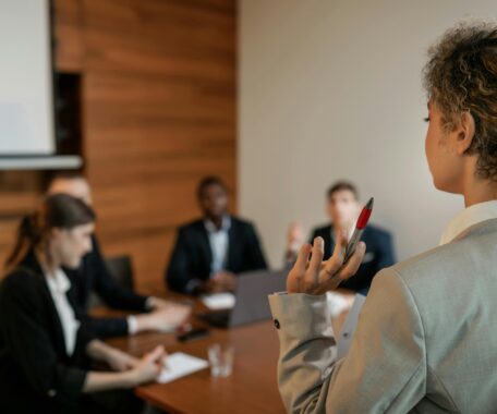 Woman in Gray Blazer Holding Pen Having Meeting with Her Colleagues