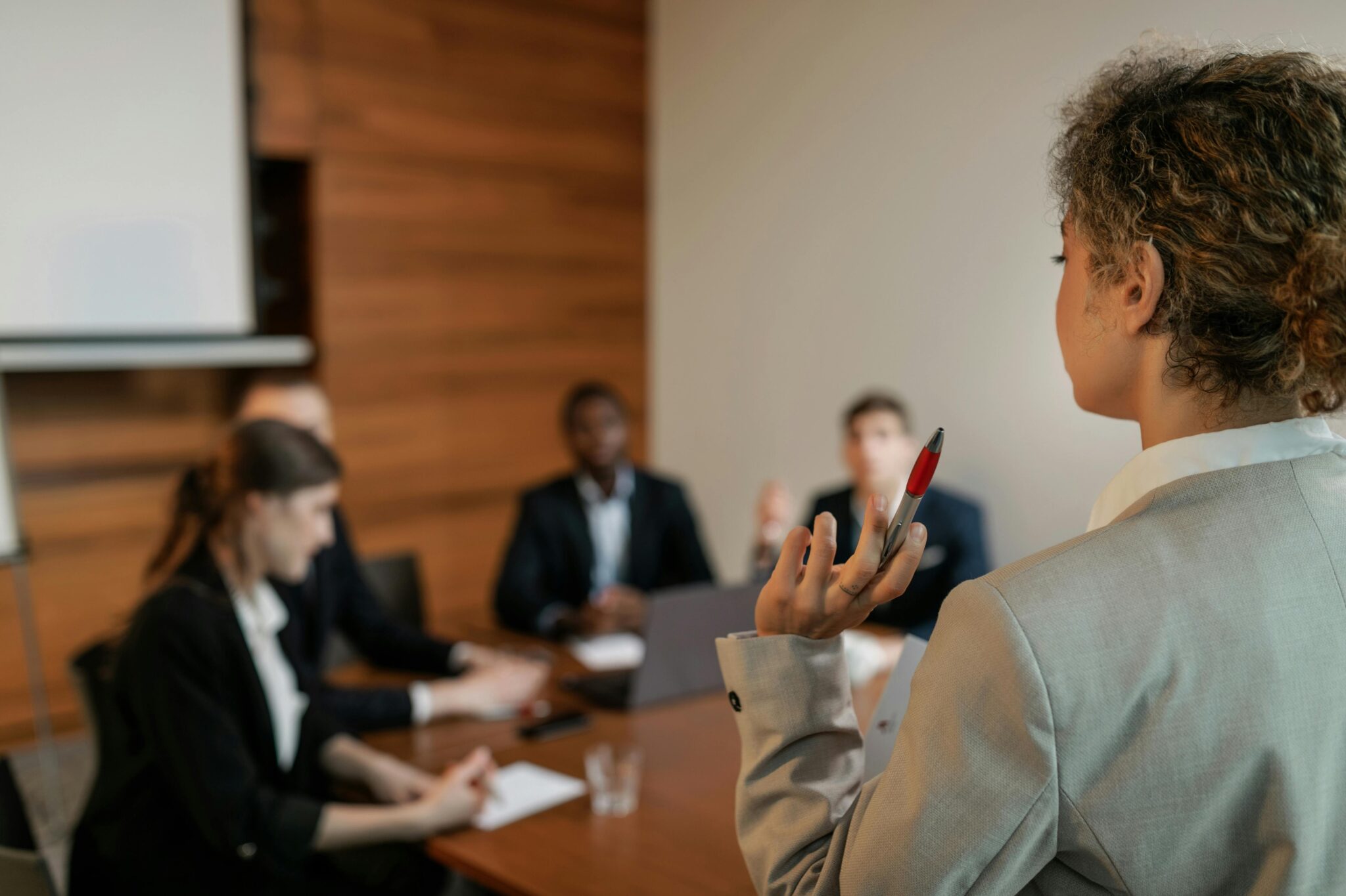 Woman in Gray Blazer Holding Pen Having Meeting with Her Colleagues