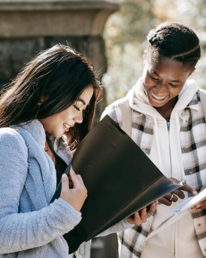 Cheerful multiracial students watching folders while studying on street