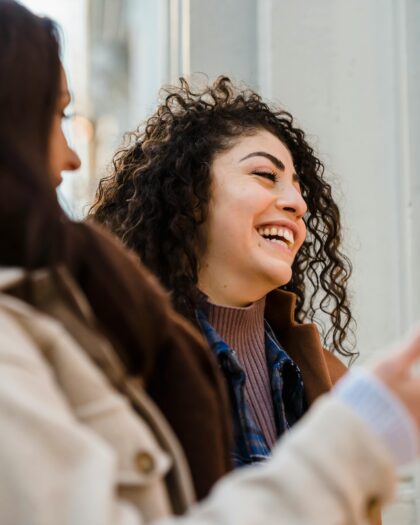 Cheerful young ladies laughing on street