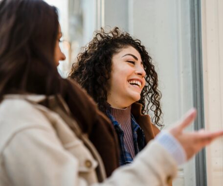 Cheerful young ladies laughing on street