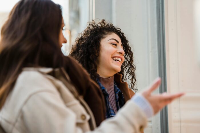 Cheerful young ladies laughing on street
