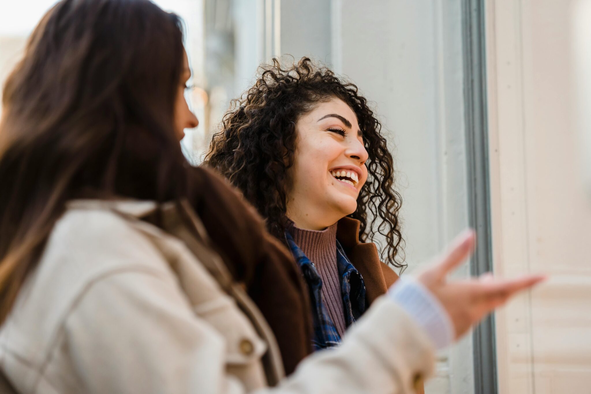 Cheerful young ladies laughing on street