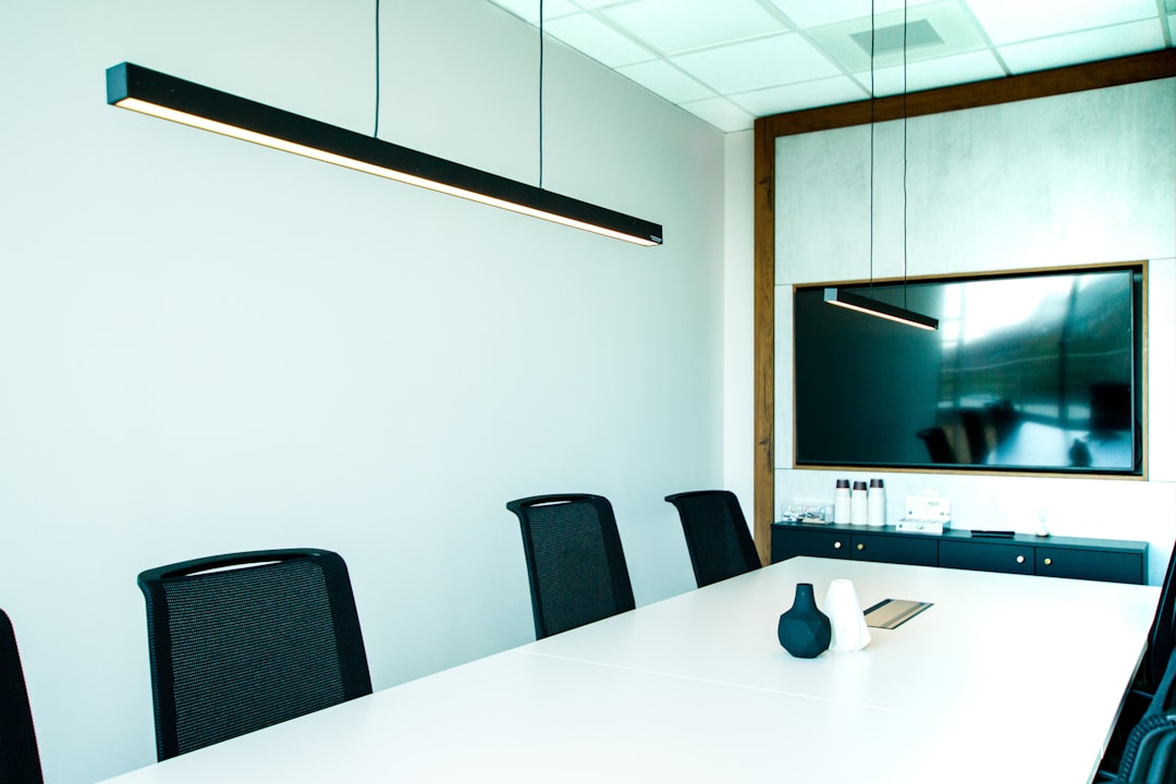 A conference room featuring a white table surrounded by black chairs.