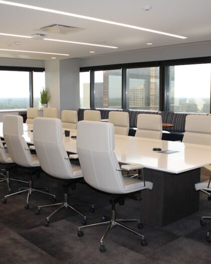 A conference room featuring white chairs arranged around a long table, designed for meetings and discussions.