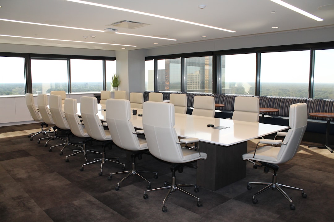 A conference room featuring white chairs arranged around a long table, designed for meetings and discussions.