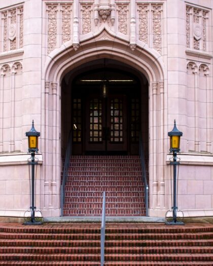 A grand arched entrance with steps and lamps.