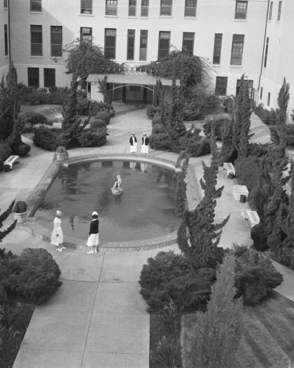 People gathered around a circular pool in a courtyard.