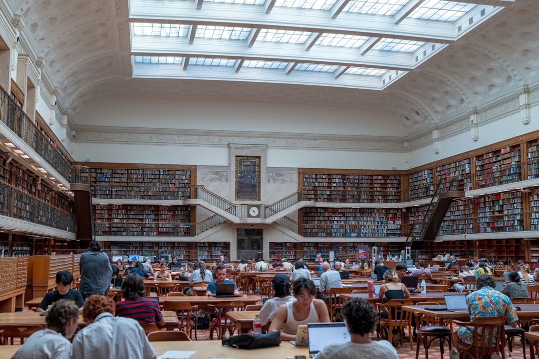 People studying in a large, ornate library with bookshelves.